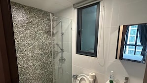 Et moderne badeværelse med bruseniche i glas, toilet og vask.