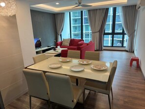 A modern living room with a dining area, a red sofa, and large windows. - A Largest Shopping Mall in Downstair (Kuching)
