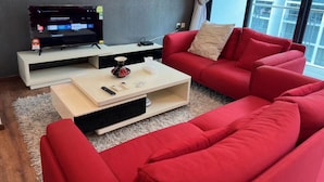 En moderne stue med en rød sofa, et fladskærms-tv og et sofabord.