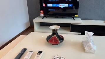 Habitación de hotel con un televisor mostrando un mensaje de error, un control remoto, una llave y un jarrón decorativo.