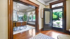 A dining area with a table and chairs, a wooden floor, and a view through a door to the outside. - Sonoma Victorian in Heart of Sonoma (Sonoma)