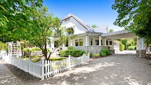 A two-story house with a covered porch, a white picket fence, and a gravel driveway. - Sonoma Victorian in Heart of Sonoma (Sonoma)