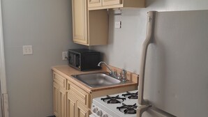 A compact kitchen with a white stove, a sink, and a microwave.