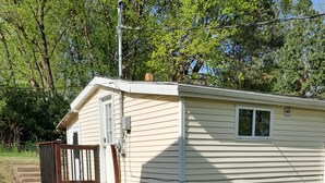 A small, single-story mobile home with a front porch and a small window.