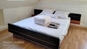 Ein ordentlich bezogenes Bett mit weißen Leinen und Kissen, ein hölzernes Kopfteil und ein kleiner Nachttisch mit einem Buch.