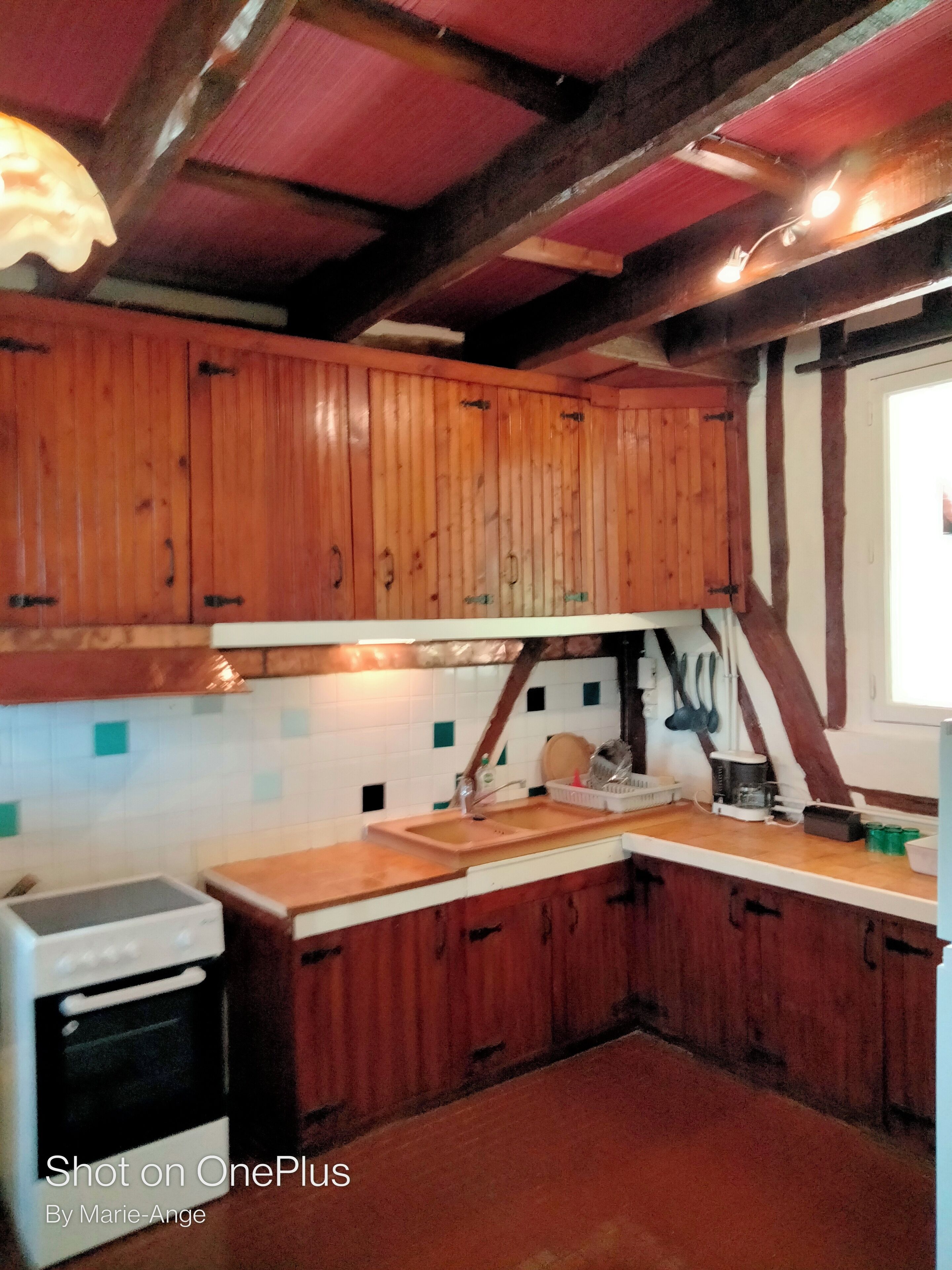 Une cuisine avec des armoires en bois, un plan de travail blanc et un four encastré.