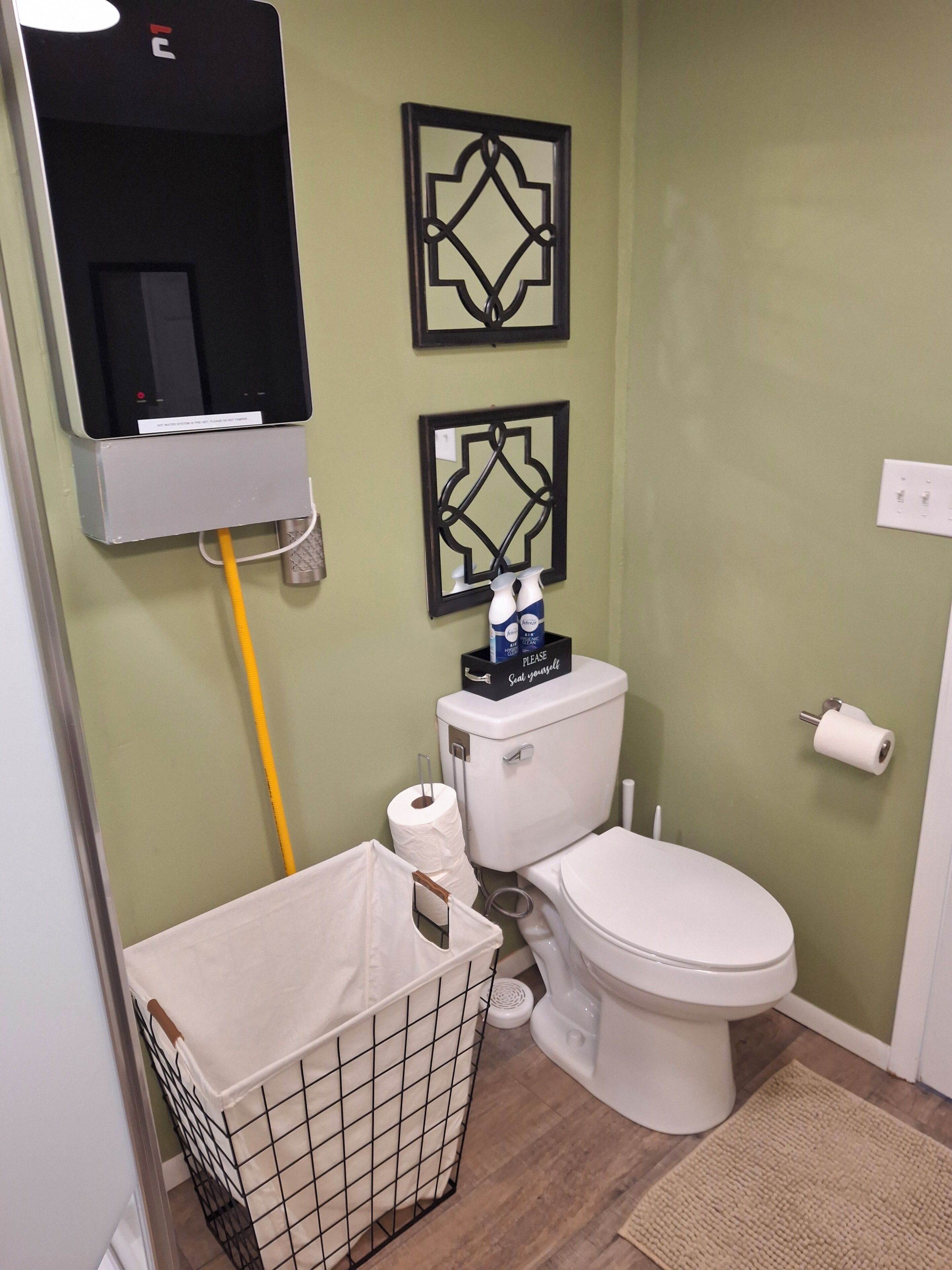 A small bathroom with a toilet, a trash bin, and two decorative wall mirrors.