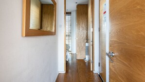 A hallway with wooden flooring, a wooden door, and a mirror on the wall.