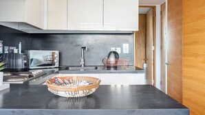 A modern kitchen with white cabinets, a black countertop, a toaster, a kettle, and a basket with items.