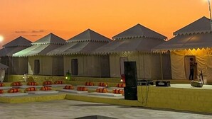A row of tents with a stage and speakers, suggesting a possible event or performance area. - Shrinath Desert Camp (Jaisalmer)