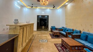 A spacious living area with a reception desk, seating arrangements, ceiling fans, and a chandelier. - Shrinath Desert Camp (Jaisalmer)