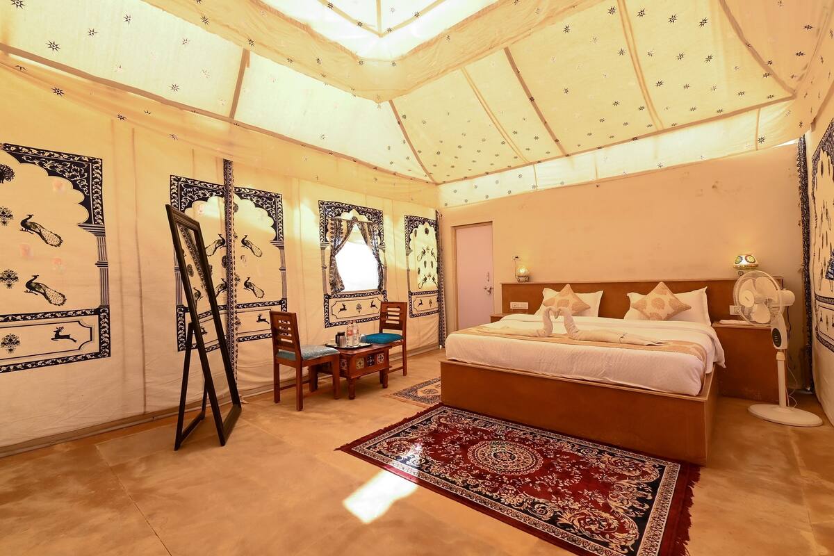 A bedroom with a bed, a desk, and chairs.