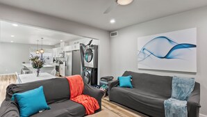 Un salon moderne avec deux canapés, une table basse et un coin repas à l’arrière-plan.