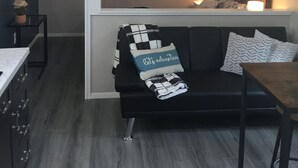 Ein kompakter Wohnraum mit Schlafempse, einer Küchenzeile, einem Essbereich und einer gemütlichen Sitzecke mit Sofa und Kissen.