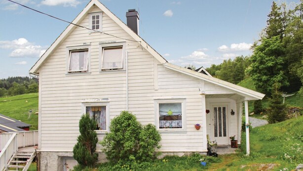 Et toetagers hvidt hus med saddeltag, en veranda og skorsten.