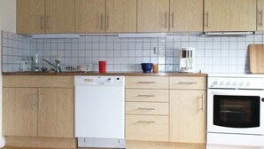 Et køkken med træskabe, opvaskemaskine, kaffemaskine og ovn.