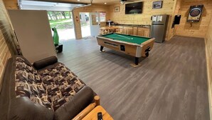 A cozy room with a pool table, a sofa, and a kitchen area. - Bluegill Bungalow-9 Miles To Dells, Pet Friendly (Briggsville)