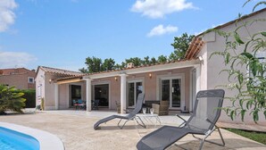 Ein Poolbereich mit Liegestühlen und einer überdachten Terrasse.