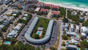 An aerial view of a coastal hotel with a curved building, a pool, and a beach in the background. - Newly remodeled, heart of Seagrove Beach, 100 yards to beach! (Santa Rosa Beach)