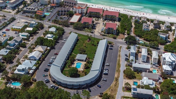 An aerial view of a coastal hotel with a curved building, a pool, and a beach in the background. - Newly remodeled, heart of Seagrove Beach, 100 yards to beach! (Santa Rosa Beach)