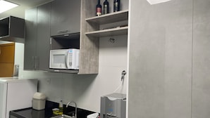 Una cocina moderna con armarios grises, un microondas integrado, un lavamanos y un dispensador de agua.
