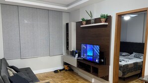Un espacio habitable compacto con televisor, sofá y cama.
