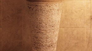 Un baño con un lavamanos grande y texturizado, un espejo encima y un secador de pelo en la pared.