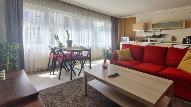 Una sala de estar con un sofá rojo, una mesa de centro de madera y un comedor con mesa y sillas.