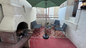 A patio with a stone fireplace, outdoor seating, and a green umbrella. - Maisonnette Centre Historique de Nîmes Tout Équipé ! (Nîmes)