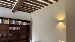 Ein Schlafzimmer mit einer Holzbücherreolen, einem Bett mit weißer Bettwäsche und einer Wandleuchte.