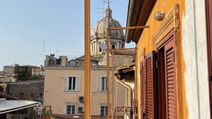 Ein Gebäude mit Kuppel und Glockenturm, ein Balkon mit Metallgeländer und ein Fenster mit Rollläden.