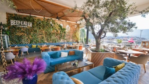 Un restaurant avec des canapés bleus, des tables en bois et une vue sur le port de plaisance.