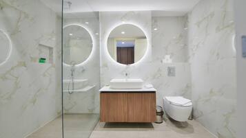 A modern bathroom with a glass-enclosed shower, a wooden vanity, and a toilet.