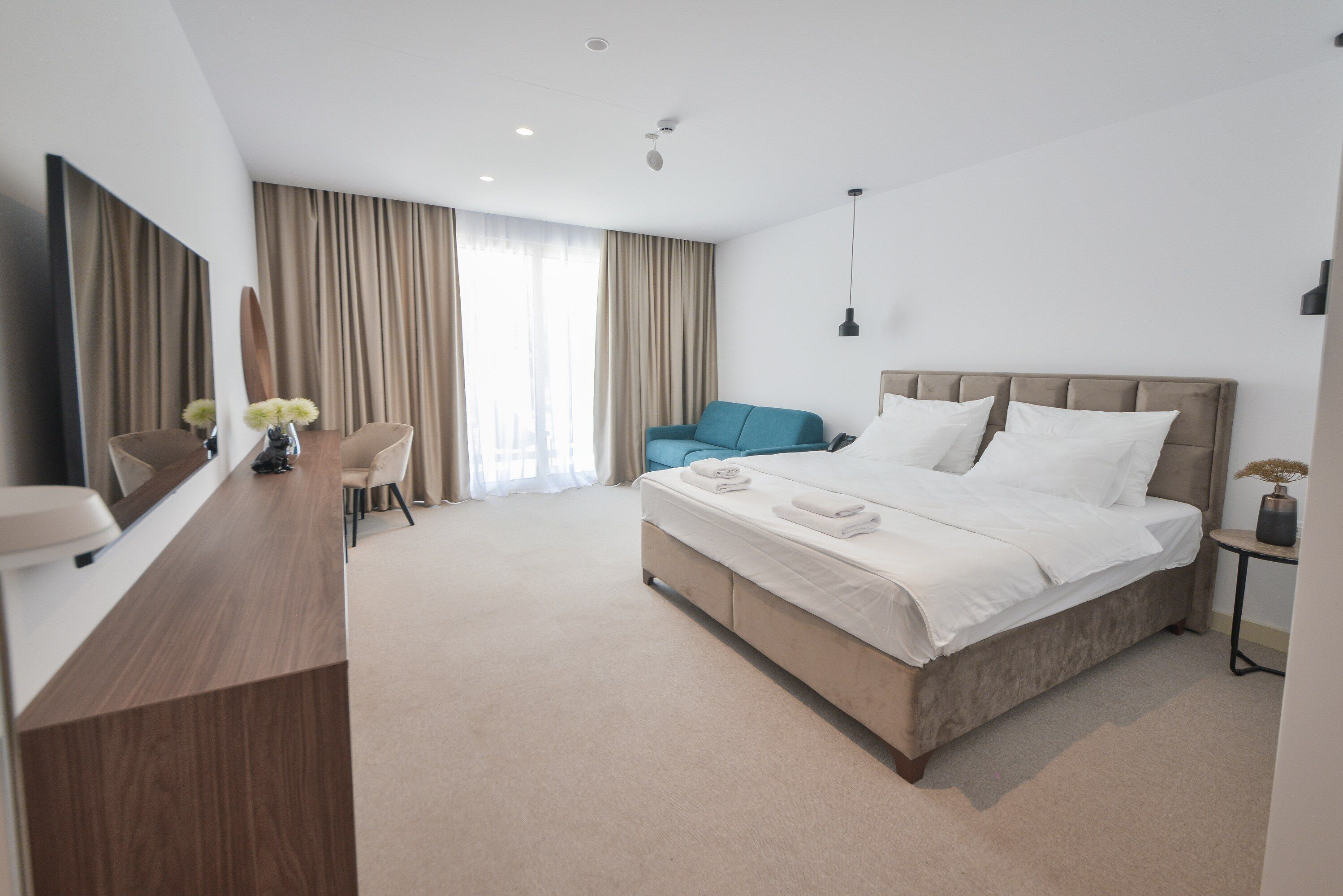 Een moderne hotelkamer met een groot bed, een bureau, een stoel en een televisie.