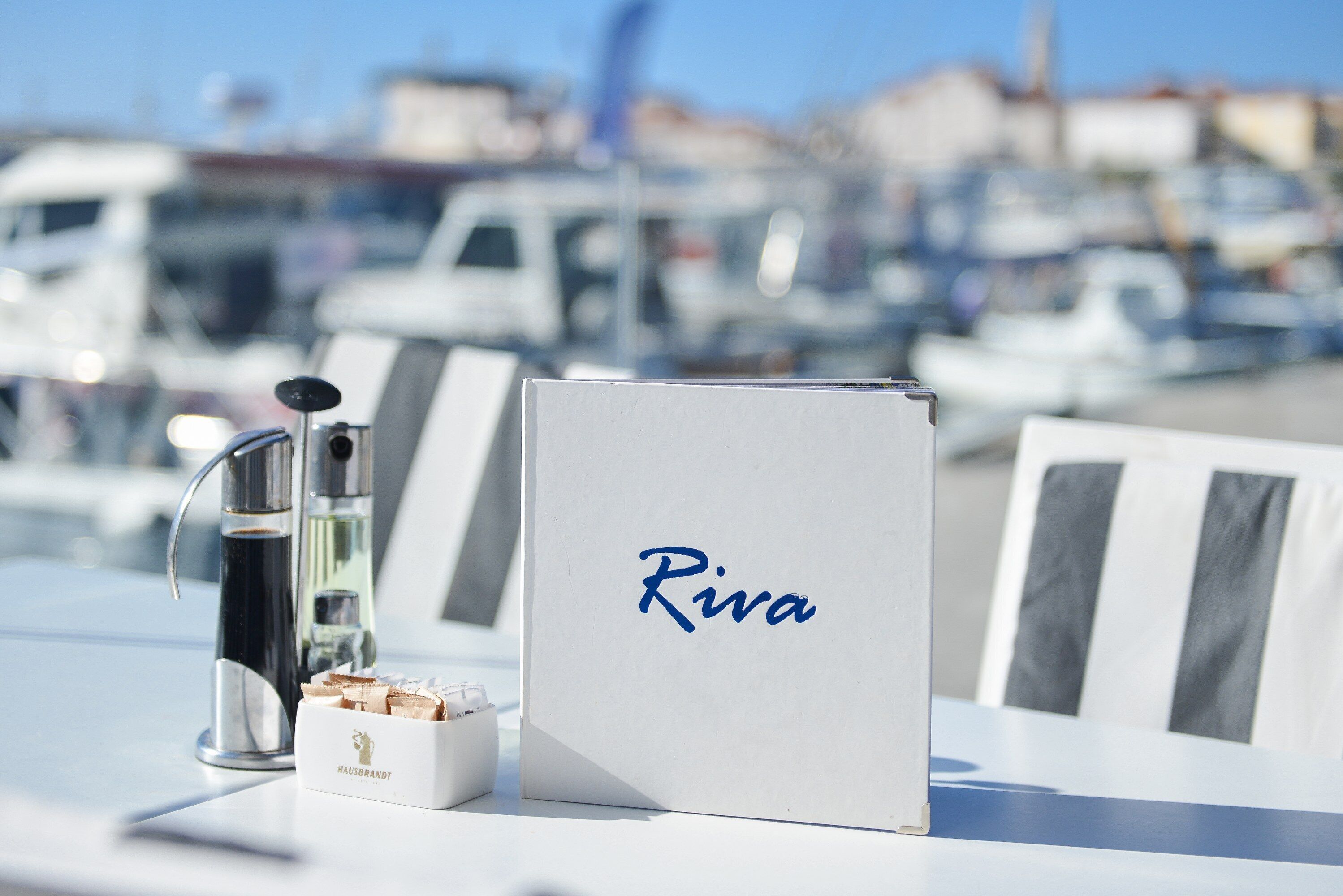 Una mesa con una máquina de café, una caja con la etiqueta "Riva" y un cuadro enmarcado.