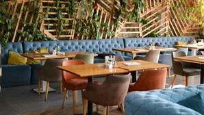 L’intérieur d’un restaurant moderne, avec un canapé bleu recouvert de tissu, des tables et des chaises en bois.