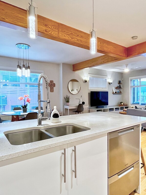 A modern kitchen with a large island, stainless steel appliances, and pendant lighting.
