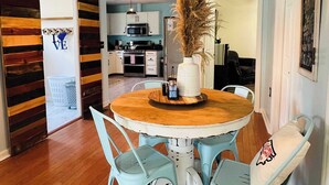 A dining area with a round wooden table, four light blue chairs, and a hanging light fixture.