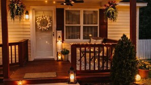 A house with a porch, a front door with a wreath, and a small Christmas tree.