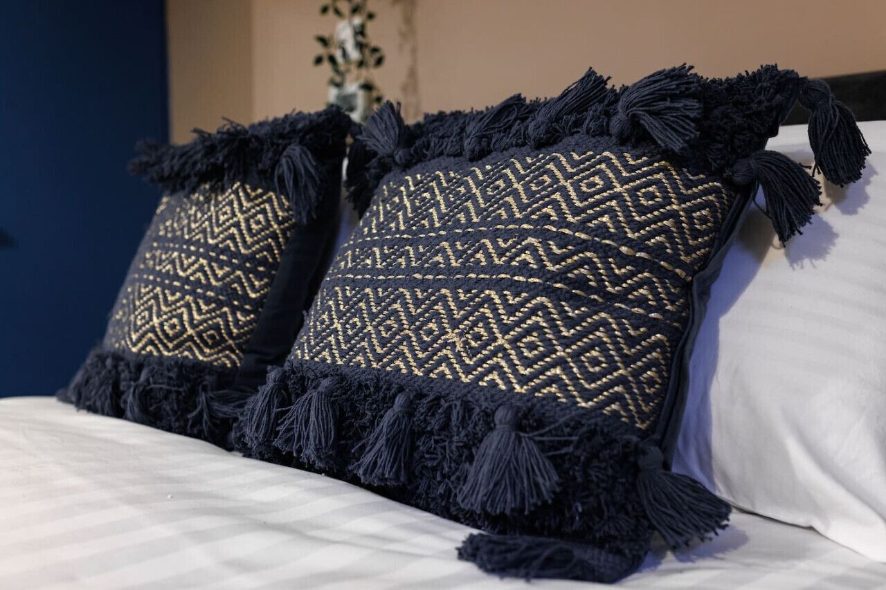 Un letto con due cuscini decorativi con motivo geometrico e frange.