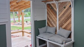 A room with a wooden ceiling, a hanging bench with cushions, a window, and a door leading outside. - One bedroom cabin minutes from the Frio River and Garner State Park! (Leakey)