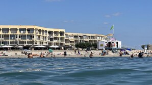 A beachfront hotel with multiple balconies, beach umbrellas, and a sandy beach. - Seaview appartment with direct acces to the beach (Palavas-les-Flots)