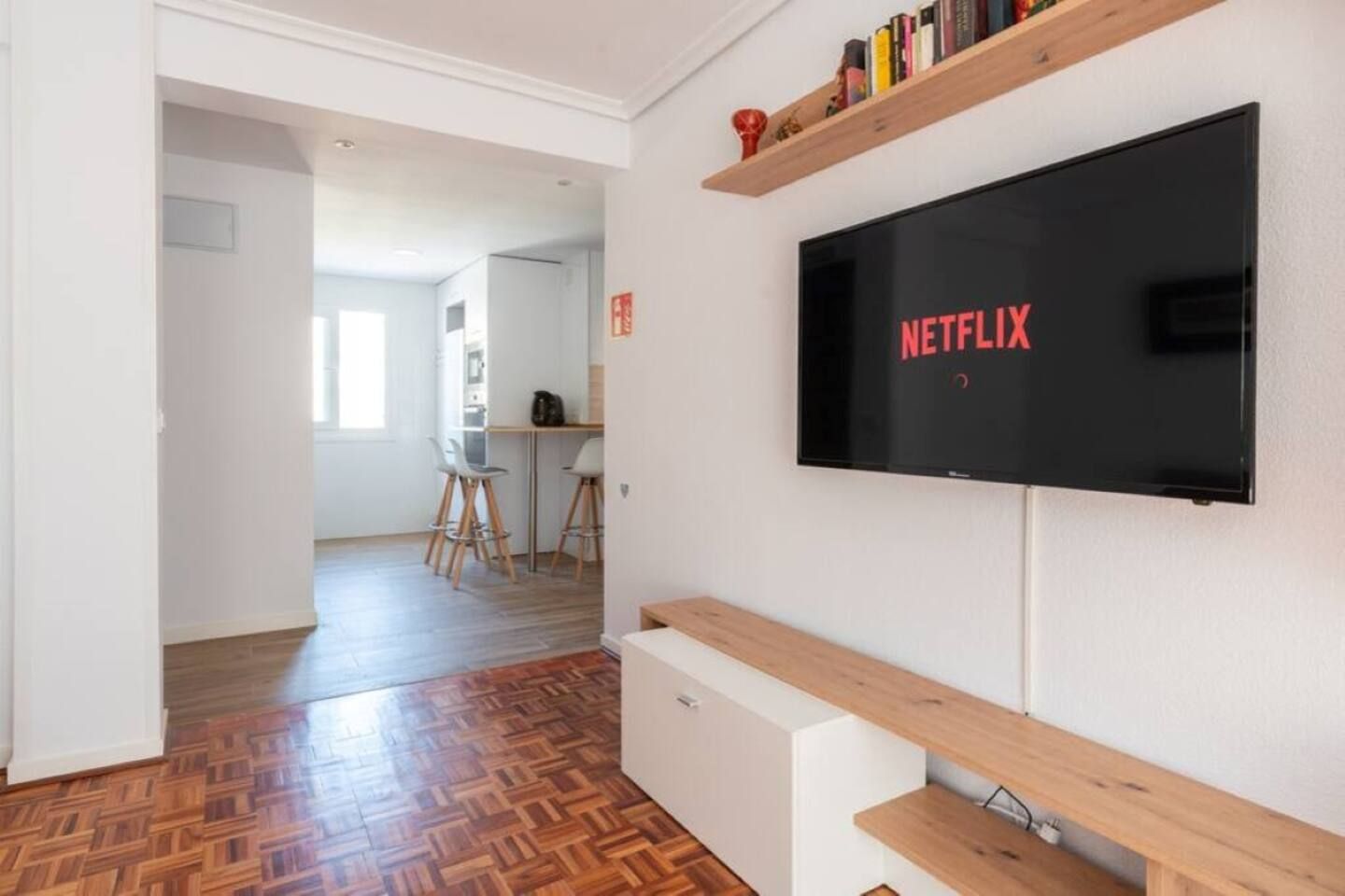 Una sala de estar moderna con un televisor de pantalla plana montado en la pared, un banco de madera y un suelo con diseño de espiga.