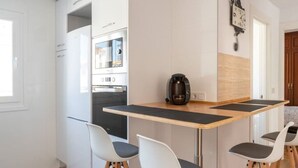 A compact kitchen with a built-in oven, a coffee maker, and a clock on the wall. - Apartamento Canalejas (Santander)