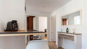 A modern kitchen with a coffee machine, a dining table, and chairs. There is a wooden countertop and a mirror above the sink. - Apartamento Canalejas (Santander)