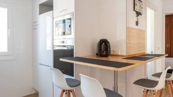 A modern kitchen with a built-in oven, a coffee machine, and a clock on the wall.