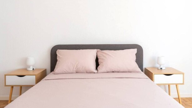 A bed with a grey headboard, two bedside tables, and a white wall. - Apartamento Canalejas (Santander)