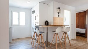 A compact kitchen with a wooden countertop, two bar stools, a coffee machine, and a clock on the wall. - Apartamento Canalejas (Santander)