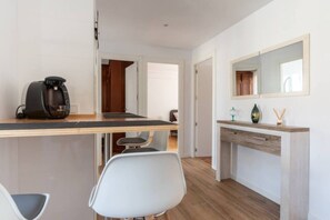 A modern kitchen with a coffee maker, a dining area with chairs, and a wooden countertop. - Apartamento Canalejas (Santander)