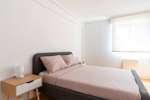 A bedroom with a bed, bedside tables, and a window. - Apartamento Canalejas (Santander)